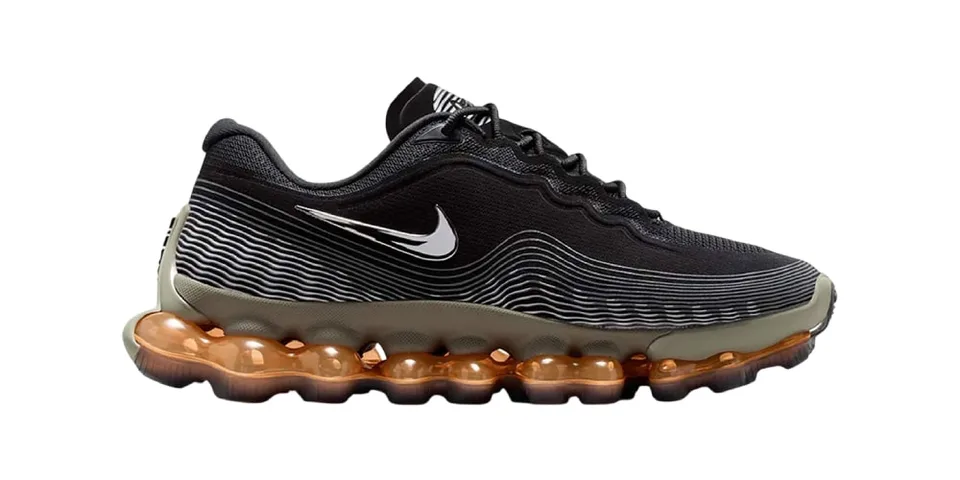 Chaussure de sport noire avec semelle à coussinets orange.