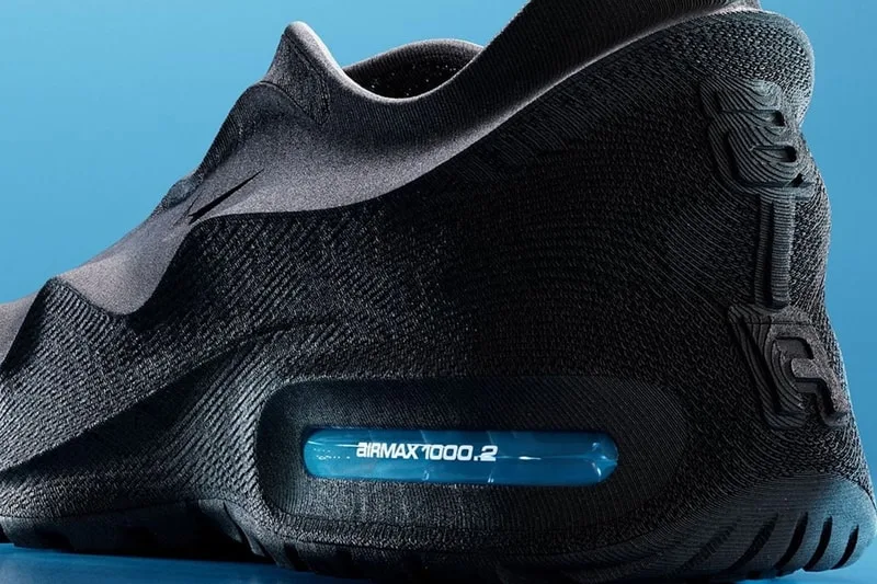 Chaussure de sport noire avec détail bleu sur le talon et fond bleu.