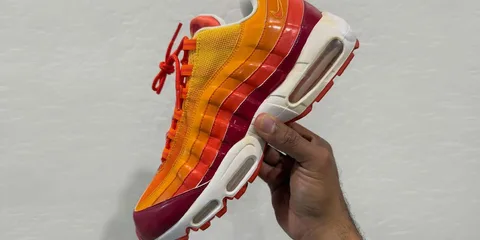 Basket multicolore tenue à la main sur fond gris.