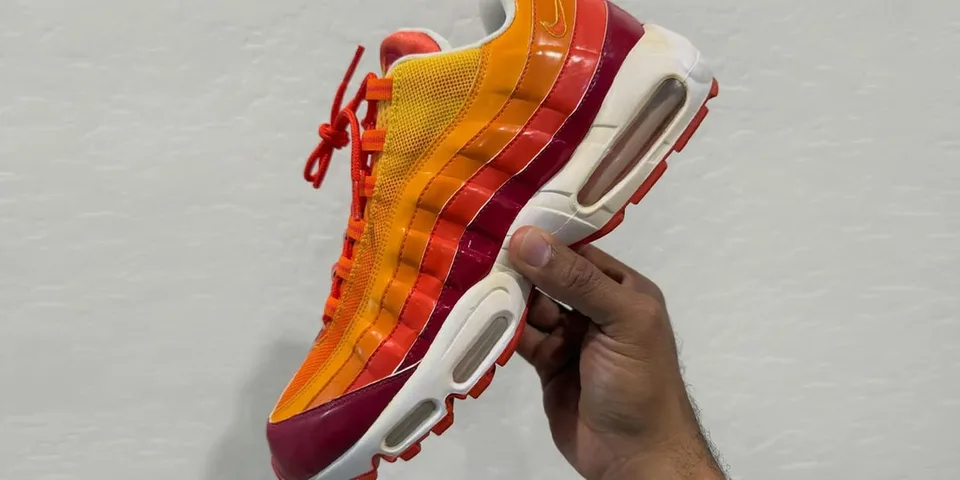 Basket multicolore tenue à la main sur fond gris.