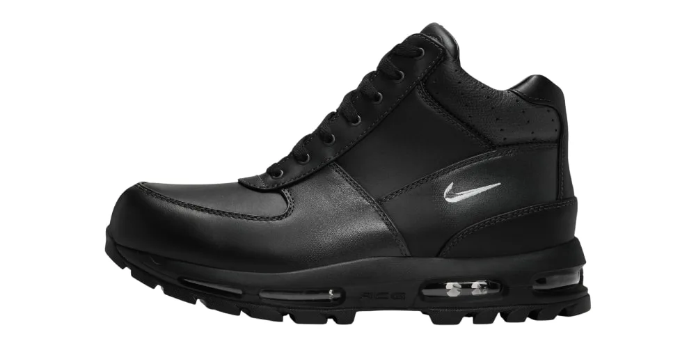 Chaussure noire avec logo blanc sur le côté, fond blanc.