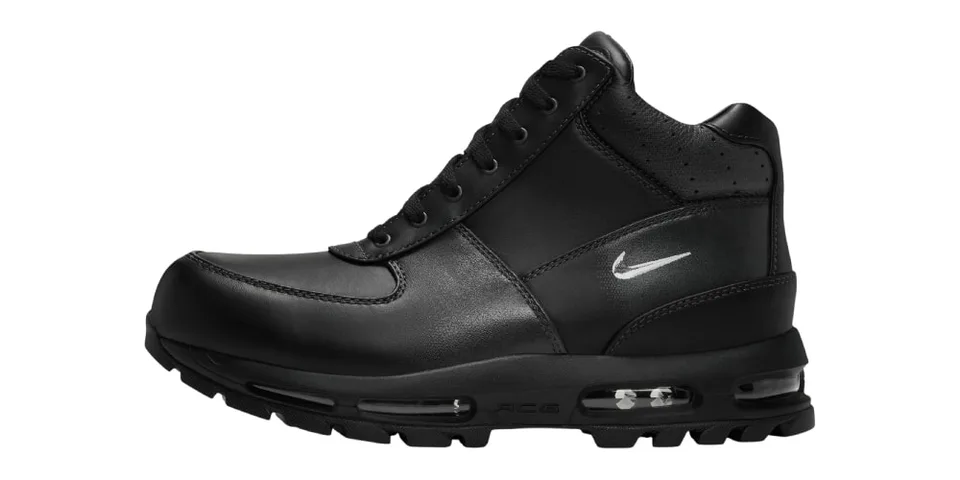Chaussure noire avec logo blanc sur le côté, fond blanc.