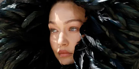 Visage d'une femme entourée de plumes noires.