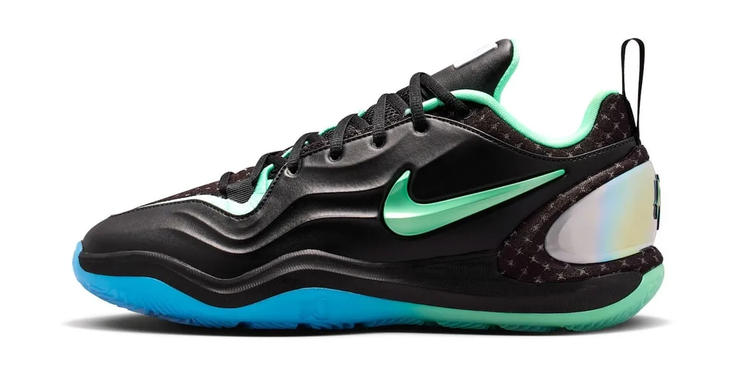 Chaussure noire avec détails verts et semelle bleue, logo visible.