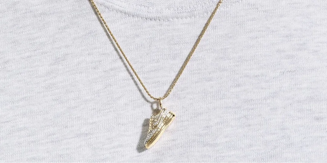 Collier avec pendentif chaussure en or sur t-shirt blanc.
