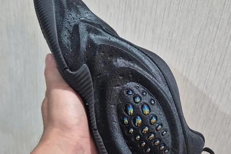 Chaussure noire futuriste avec détails en forme de gouttes iridescentes.