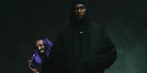 Deux personnes posent avec des baskets violettes, vêtues de noir.