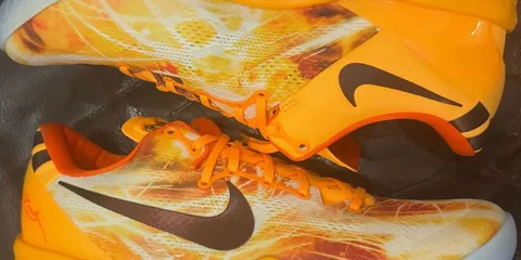 Chaussures de sport orange avec logo swoosh noir sur les côtés.
