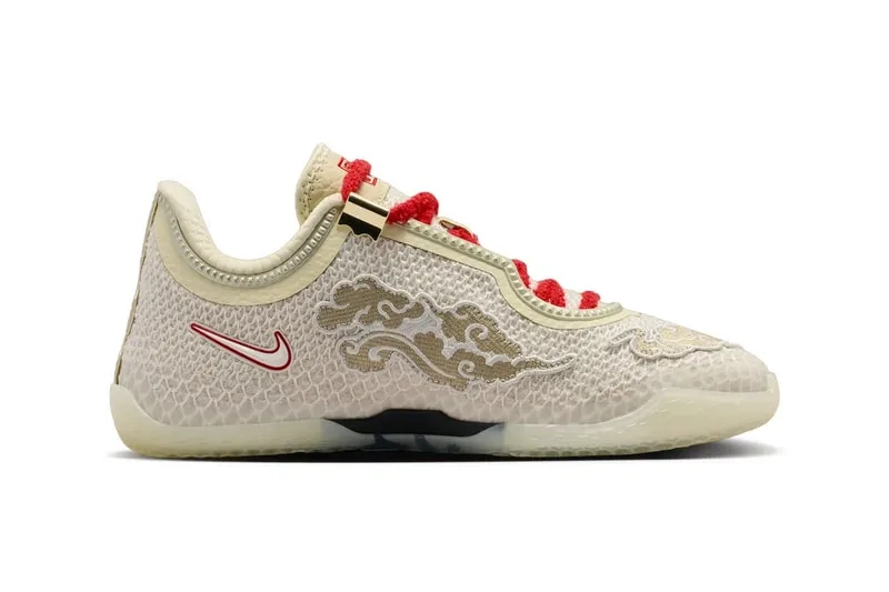 Chaussure Nike beige avec motifs dorés et lacets rouges.