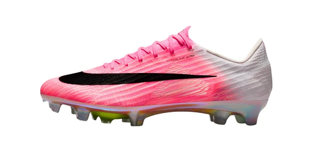 Chaussure de football rose et blanche avec motif noir et crampons.