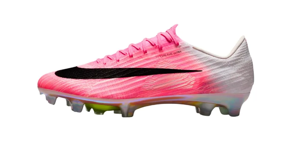 Chaussure de football rose et blanche avec motif noir et crampons.