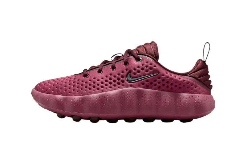 Chaussure de sport rouge avec logo Nike, semelle à crampons.
