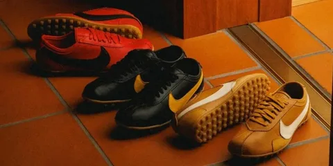 Trois paires de chaussures de sport colorées sur le sol en carrelage.