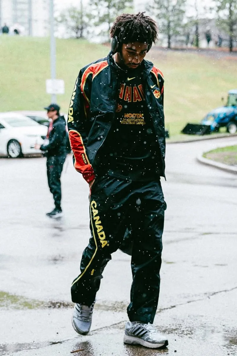 Personne marchant sous la pluie en vêtements de sport noirs avec écouteurs.