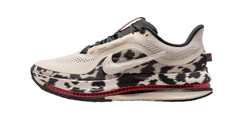 Chaussure de sport beige et noire avec semelle rouge visible.