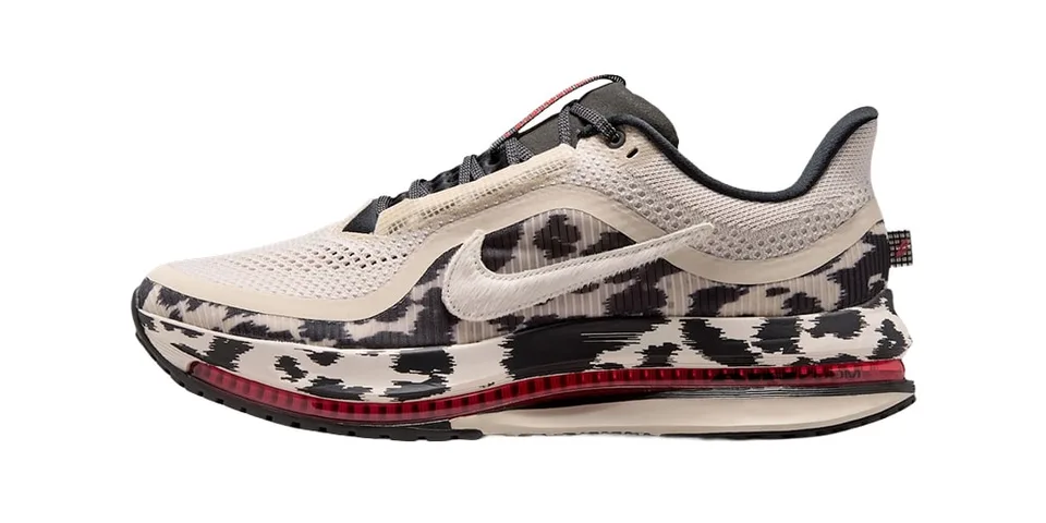 Chaussure de sport beige et noire avec semelle rouge visible.