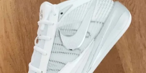 Chaussure blanche avec motif et logo Nike sur fond bois clair.