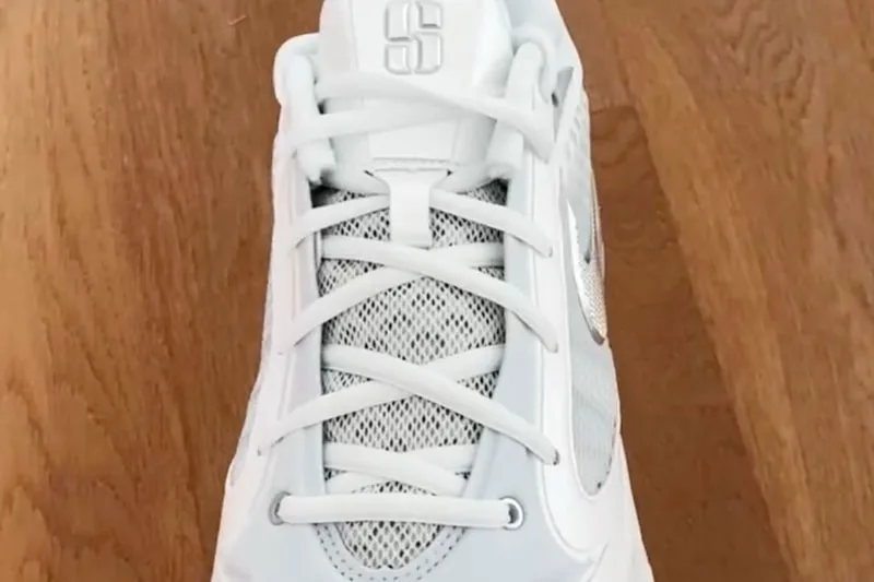 Chaussure blanche sur fond de bois, vue de dessus, lacets croisés.