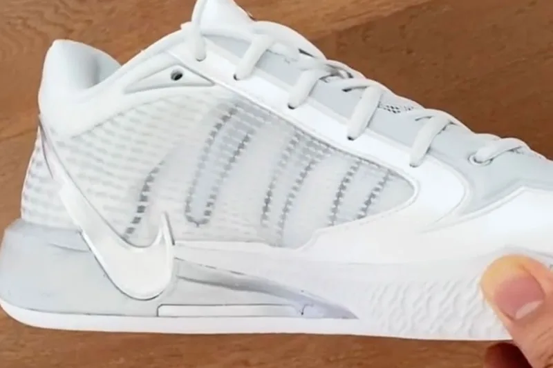 Chaussure de sport blanche avec logo Nike, sur fond en bois.