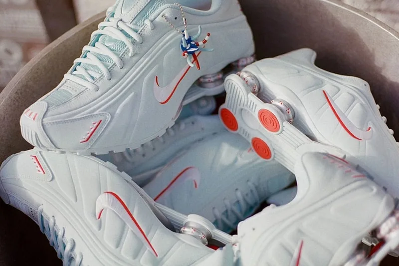 Chaussures de sport blanches avec logo rouge et personnage suspendu.