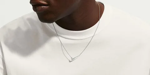 Homme avec collier et t-shirt blanc, gros plan