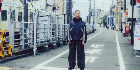 Un homme se tient au milieu d’une rue étroite au Japon.