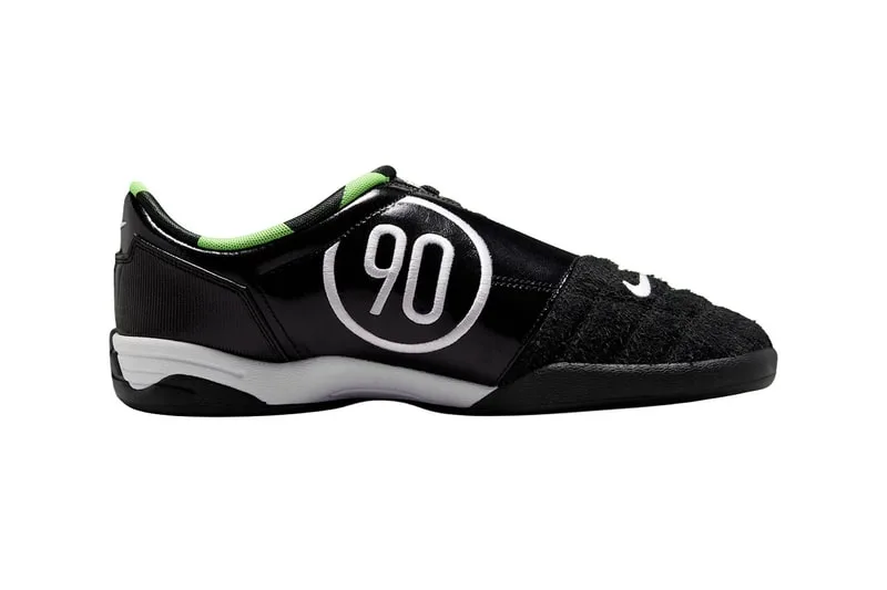 Chaussure de sport noire avec logo '90' et détails verts.