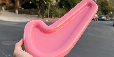 Objet rose en forme de pipe tenu à la main dans une rue