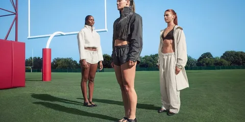 Trois mannequins posent sur un terrain de sport en plein air.