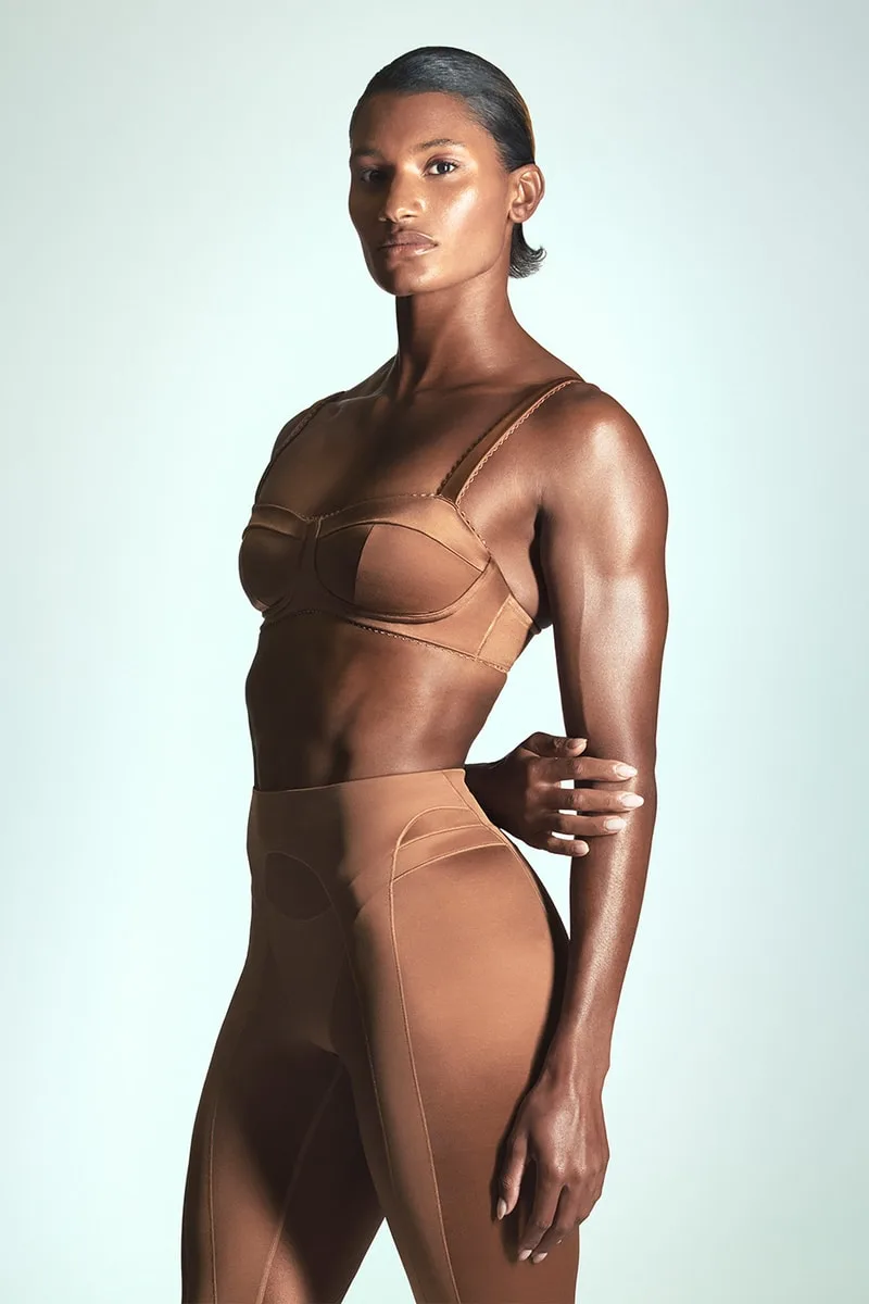 Femme en tenue marron moulante posant de profil.