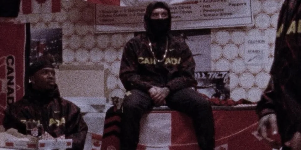 Deux personnes en noir, vêtements marqués Canada, assises dans un décor vintage.