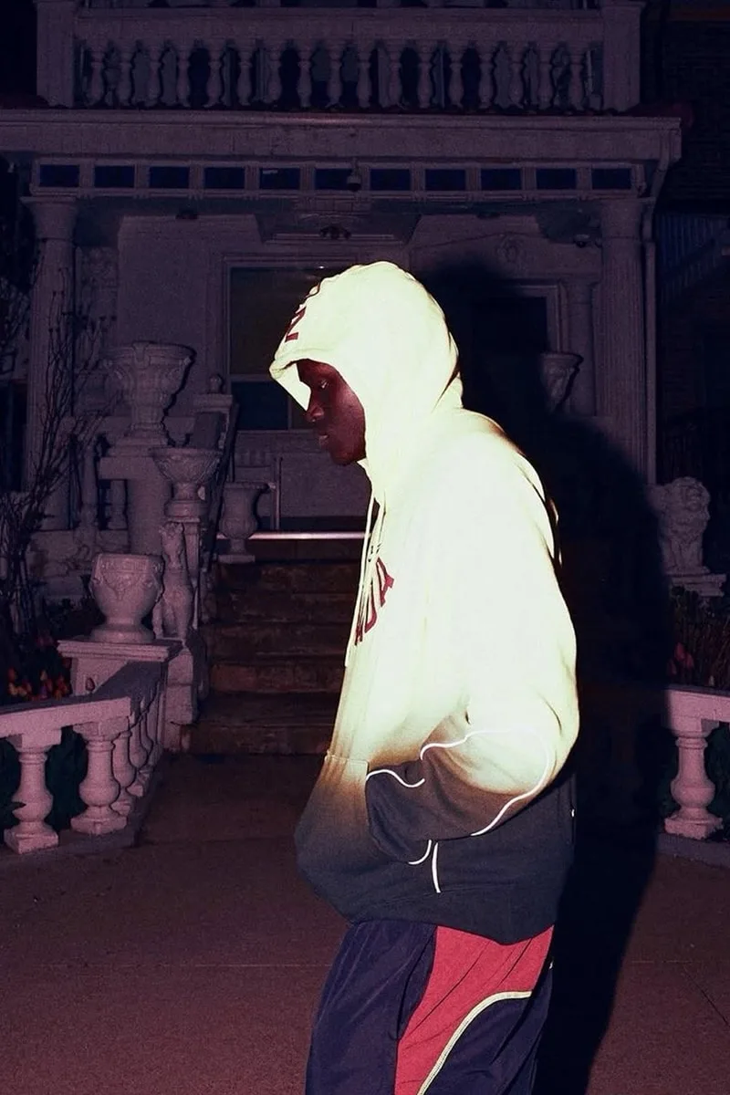 Personne en sweat à capuche devant un bâtiment la nuit.