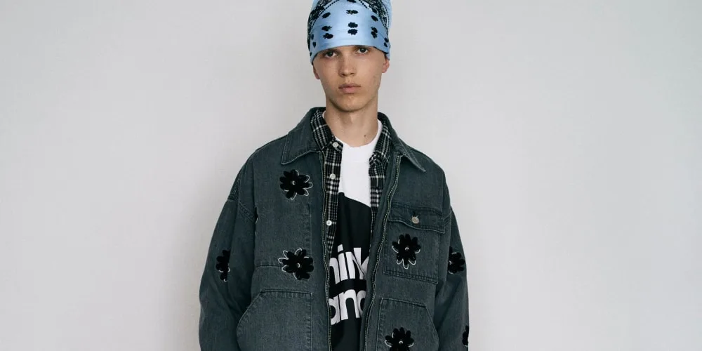 Personne portant une veste en jean avec fleurs noires et bandana bleu.