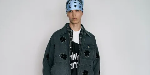 Personne portant une veste en jean avec fleurs noires et bandana bleu.