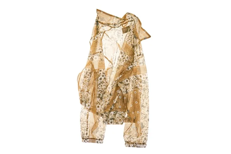 Chemisier transparent à motifs floraux beige et blanc sur fond blanc.