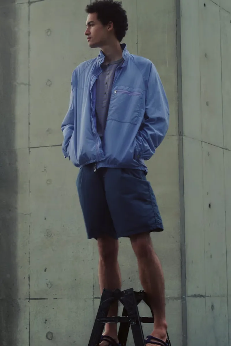 Homme debout sur une échelle avec une veste bleue et un short.