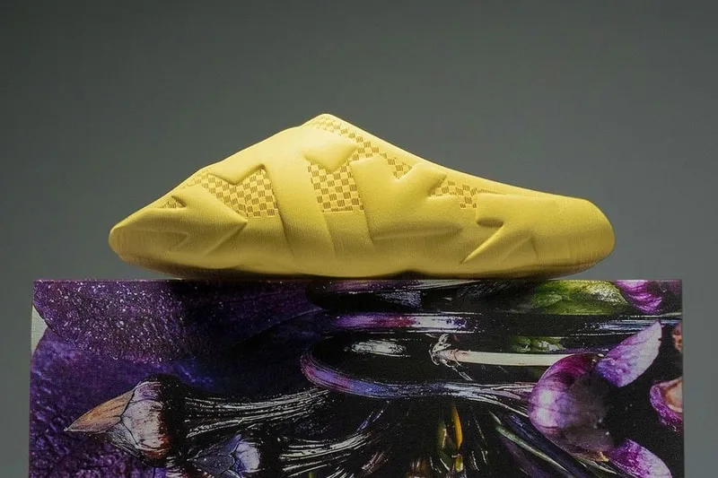 Chaussure jaune avec motifs géométriques, posée sur une surface artistique colorée.