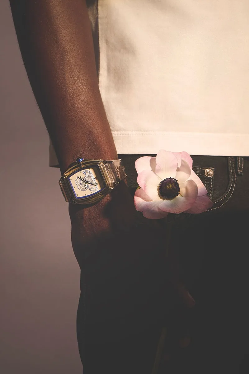 Montre avec fleur rose tenue par une main.