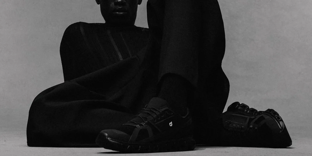 Personne vêtue de noir avec des chaussures noires, posant de manière artistique.