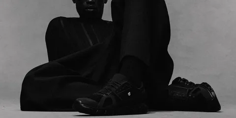 Personne vêtue de noir avec des chaussures noires, posant de manière artistique.