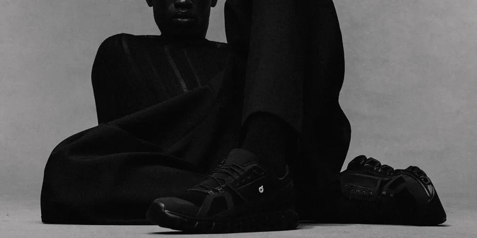Personne vêtue de noir avec des chaussures noires, posant de manière artistique.