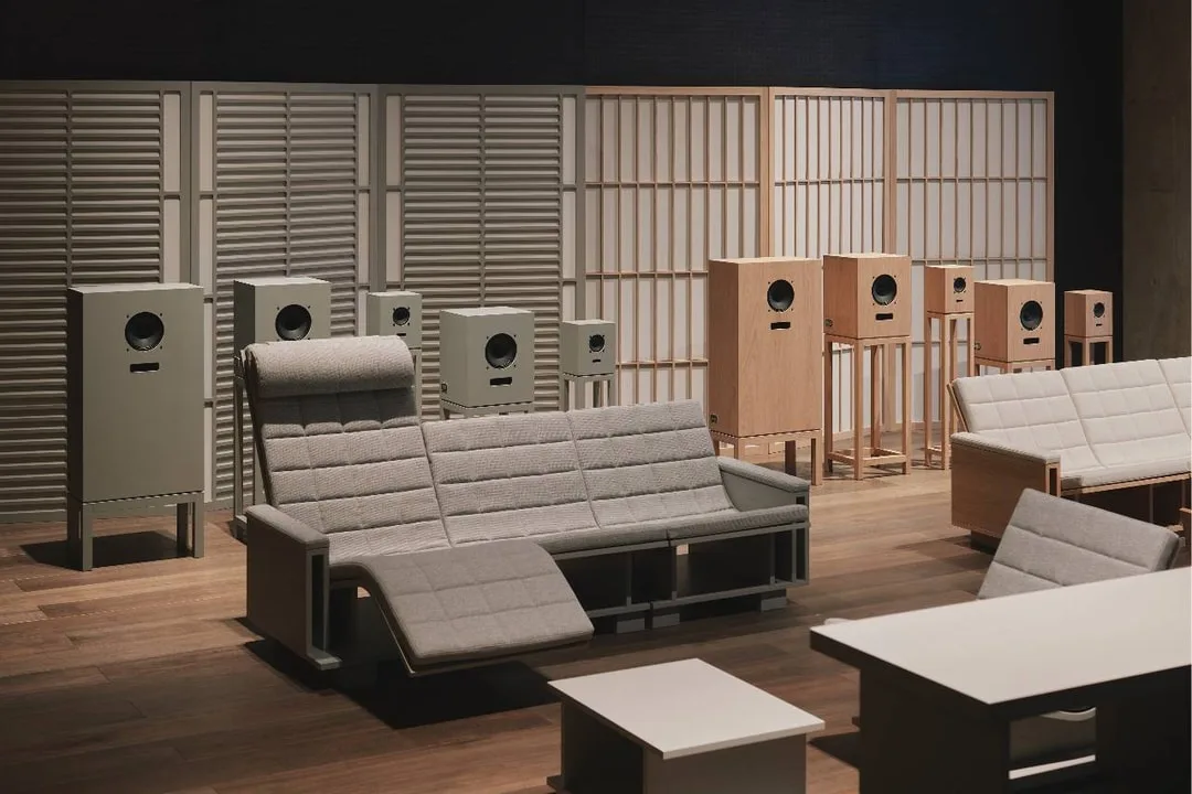 Salon contemporain avec canapé gris, fauteuils et enceintes en bois devant des panneaux japonais.