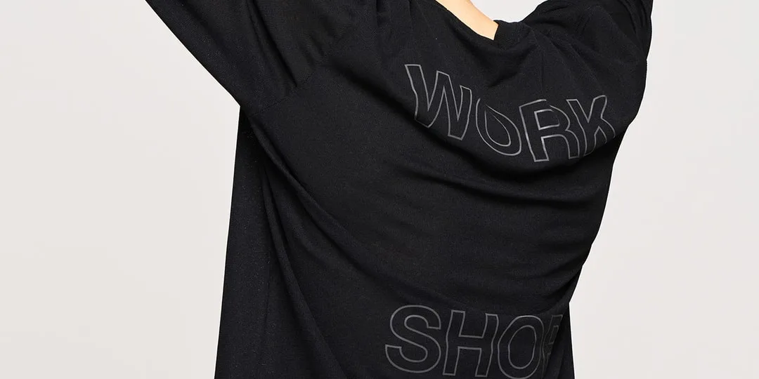Personne portant un t-shirt noir avec 'WORK SHOP' écrit dessus, de dos.