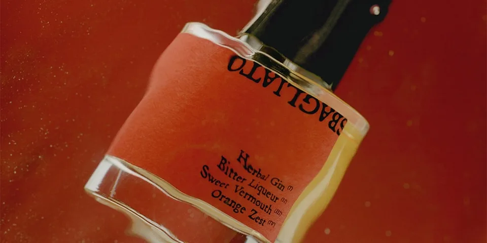 Bouteille de parfum avec étiquette rouge et texte.