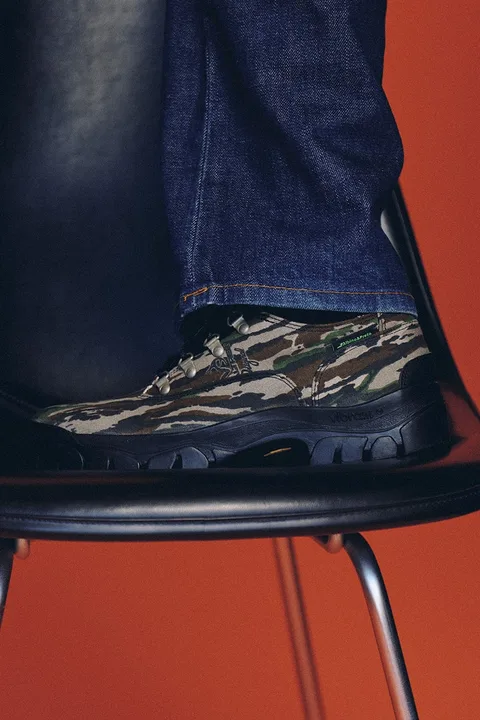 Chaussure camouflage sur chaise noire avec fond rouge.