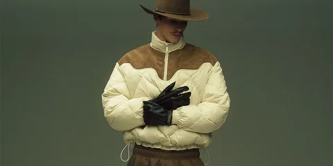Homme en chapeau et manteau rembourré avec gants noirs