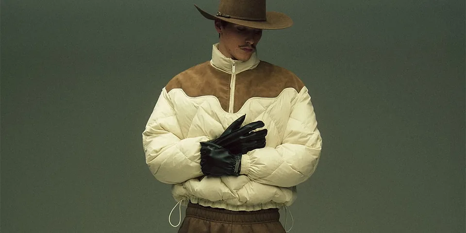 Homme en chapeau et manteau rembourré avec gants noirs