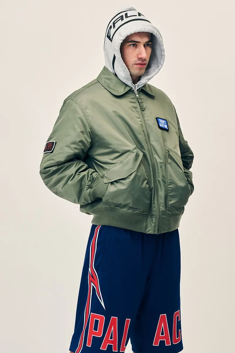 Homme en veste verte, short bleu et sweat à capuche gris.