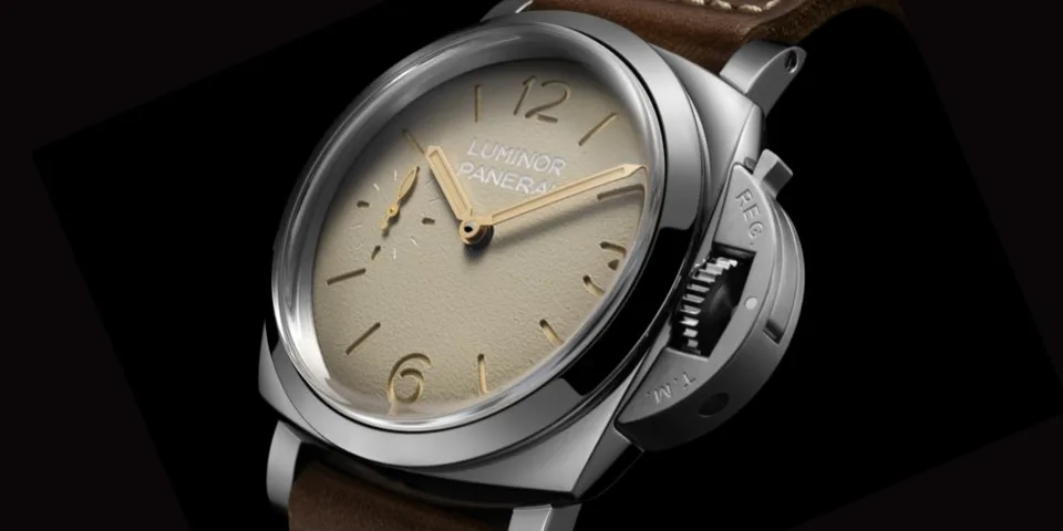 Montre avec cadran beige et bracelet en cuir marron.