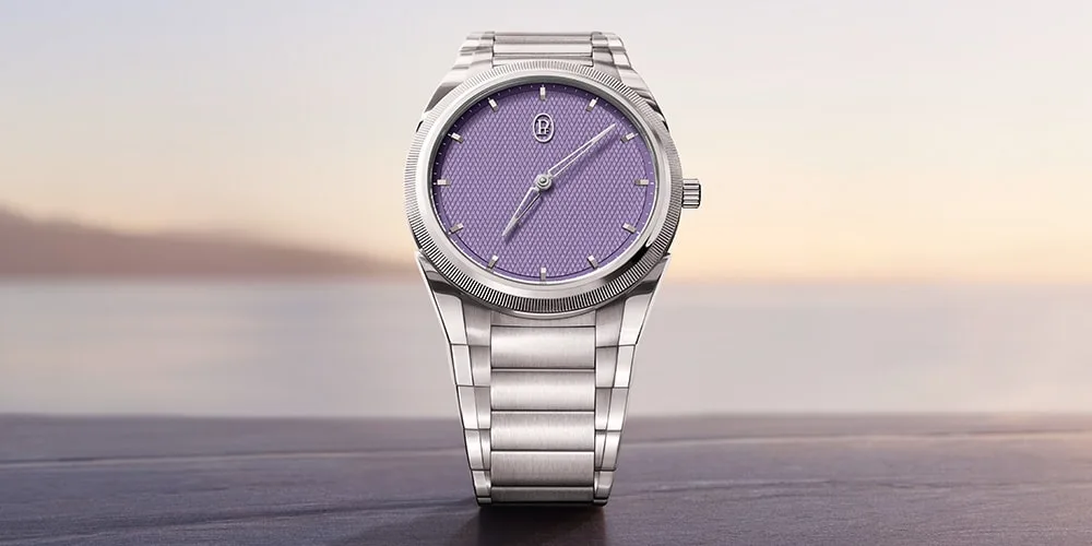 Montre avec cadran violet et bracelet en métal argenté devant un paysage flou.
